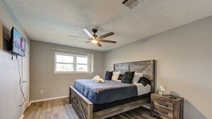 A bedroom with a bed, a nightstand, a ceiling fan, a window, and a wall-mounted TV. - Private Pool Paradise in La Porte. Family & Work Stays Welcome (La Porte)