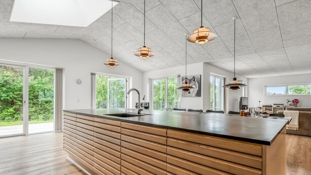 Une cuisine moderne dotée d’un grand îlot central, de luminaires suspendus et de grandes fenêtres.