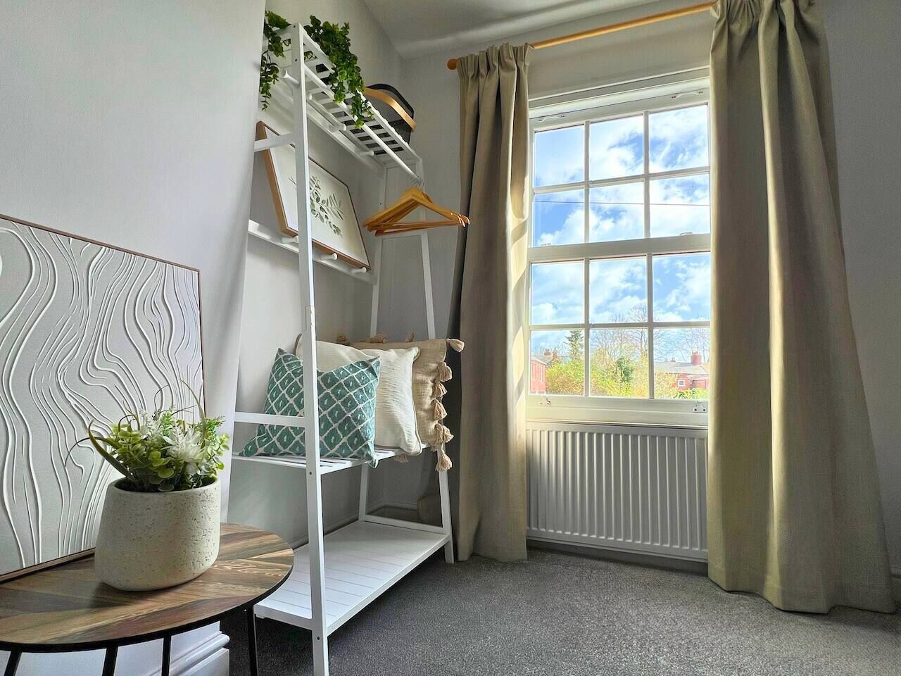 A room with a bunk bed, a radiator, a window with curtains, a plant on a table, and a wall with a textured design.