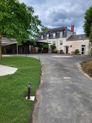A residential property with a driveway, a covered patio, and a well-maintained lawn. - En face du parc de Loire d' Orléans,maison classée "remarquable" avec piscine (Saint-Denis-en-Val)