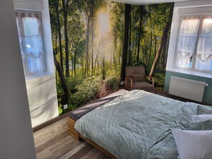 A bedroom with a bed, a chair, and a large forest mural on the wall. - En face du parc de Loire d' Orléans,maison classée "remarquable" avec piscine (Saint-Denis-en-Val)