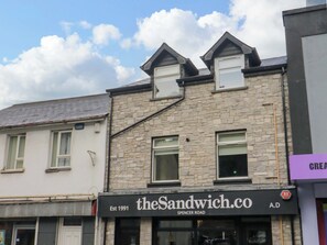 A building with a stone facade, a sign for 'theSandwich.co' on the ground floor, and a clear sky above. - Suite 33A (Londonderry)