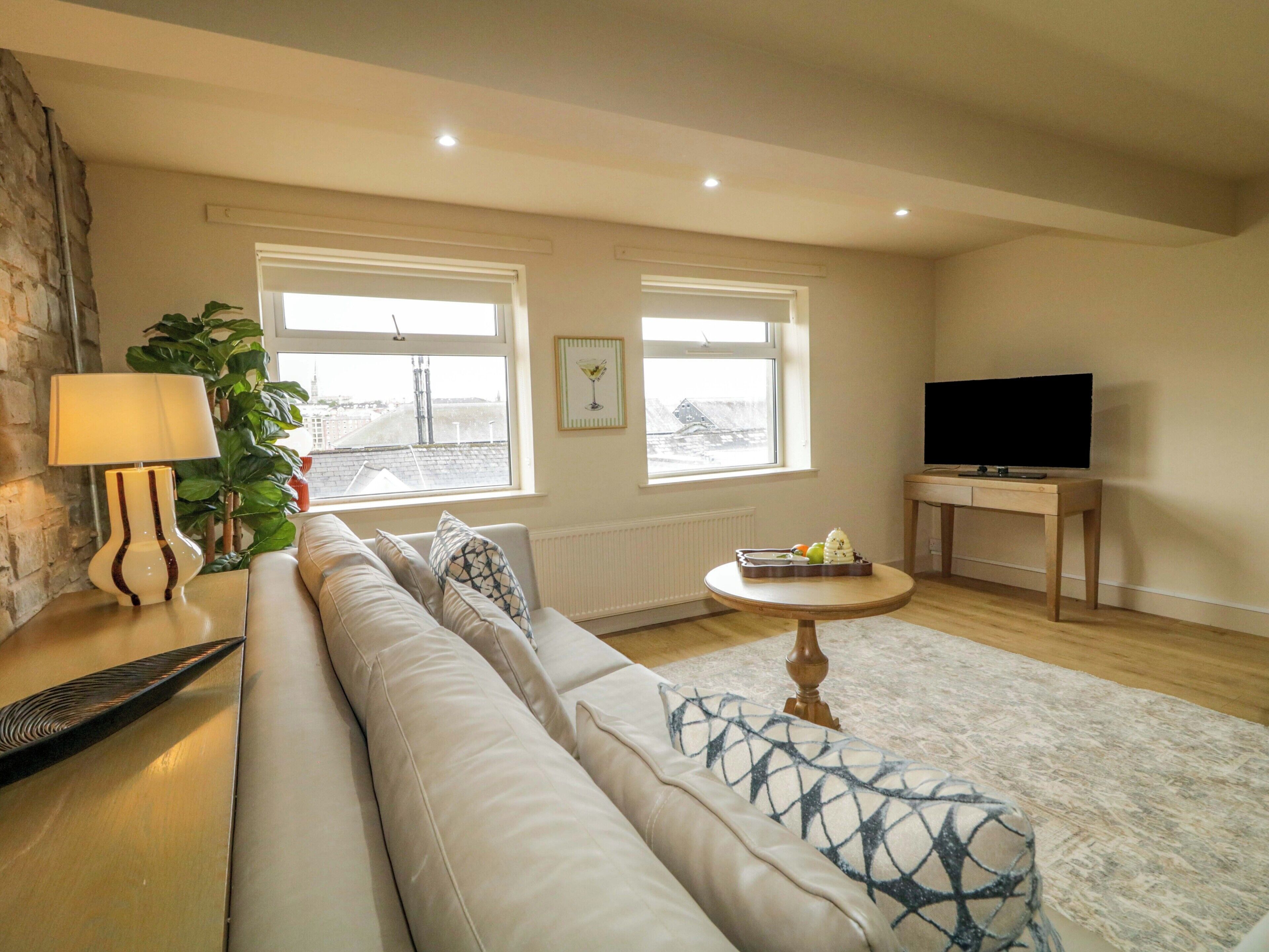 A living room with a sofa, a lamp, a TV, and a window with a view.