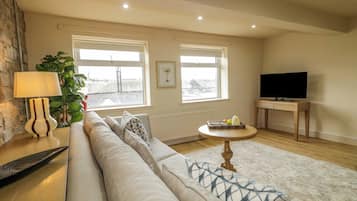 A living room with a sofa, a lamp, a TV, and a window with a view.