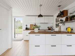 A modern kitchen with white cabinets, a wooden countertop, and a yellow kettle. - "Raadengaard" - 400m from the sea by Interhome (Knebel)