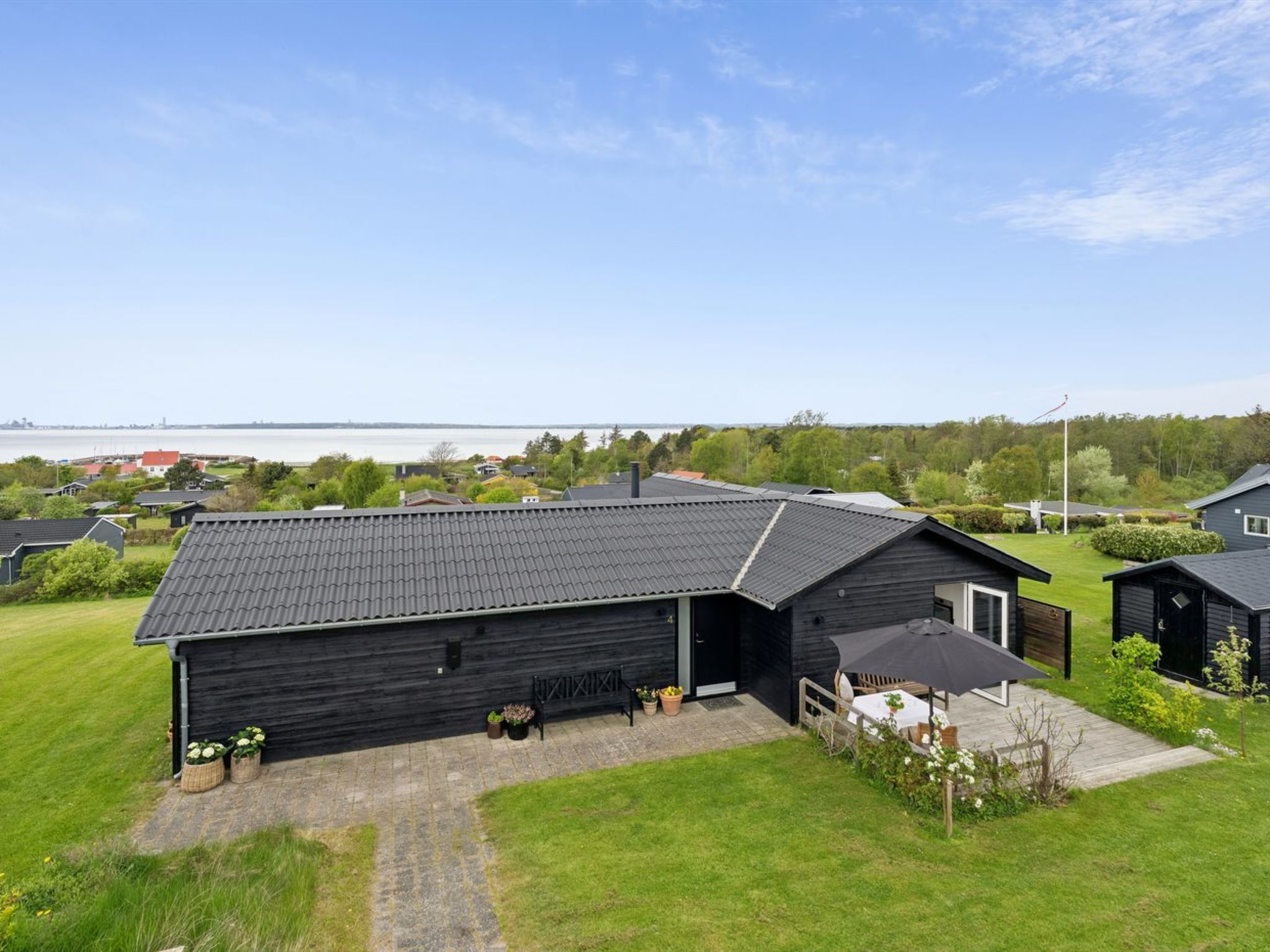 A black building with a sloped roof, a covered outdoor seating area, and a view of a body of water in the background.
