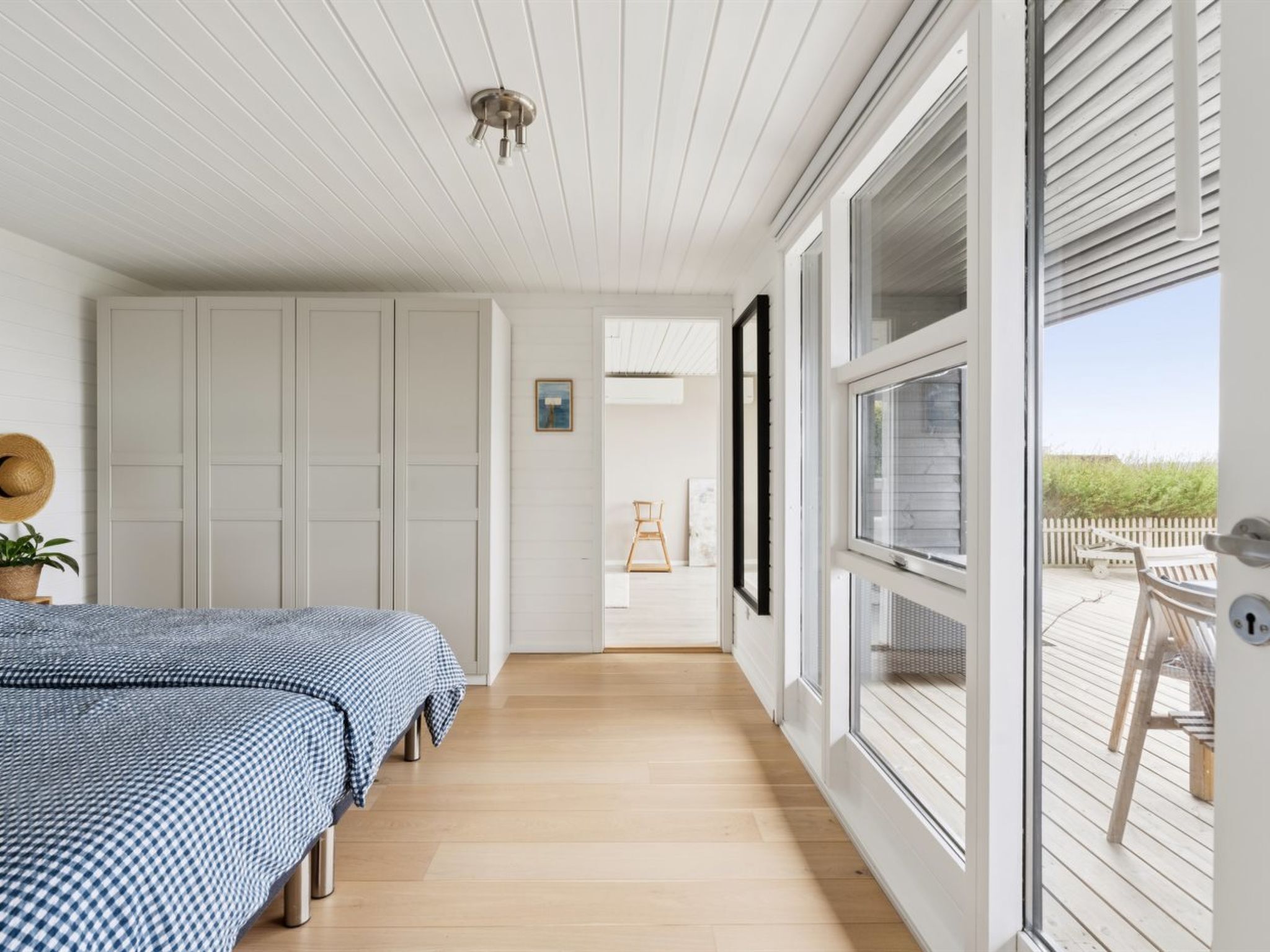 A bedroom with a bed, a wardrobe, a door leading to a balcony, and a ceiling light.