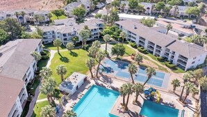 Et hotel med flere etager, en central swimmingpool, palmer og en basketballbane.