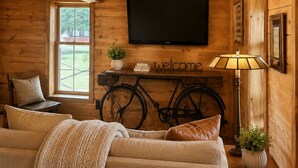A cozy room with a sofa, a television, a bicycle, and a lamp.