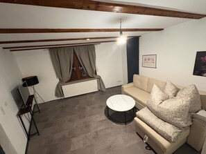 Ein Wohnzimmer mit einer Couch, einem runden Couchtisch, einer Heizung und einer Deckenleuchte.