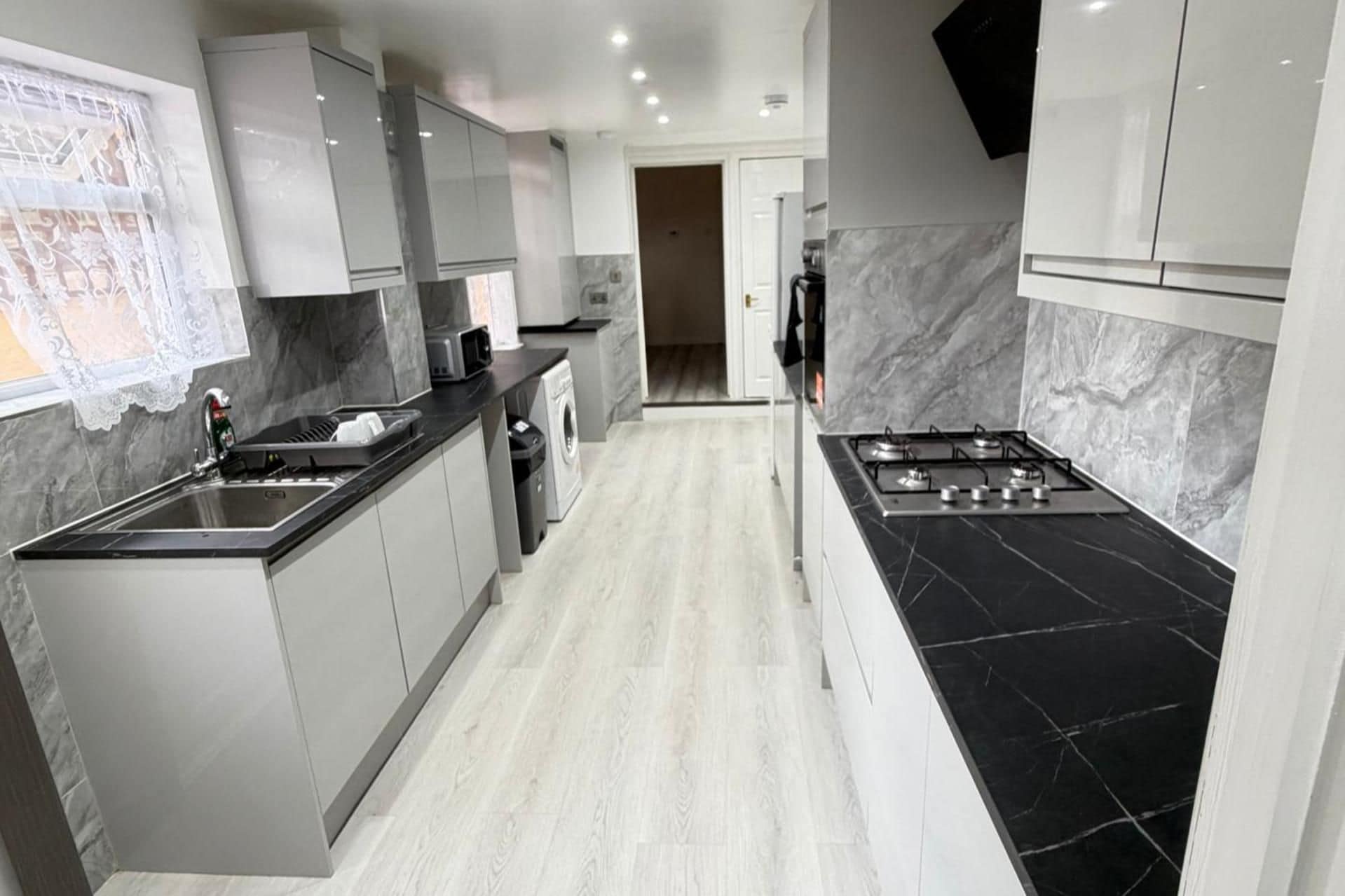 A modern kitchen with a central island, stainless steel appliances, and a marble backsplash.