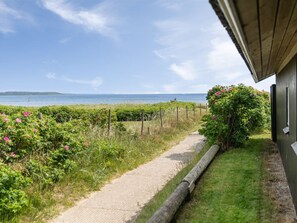 A pathway leading to a building with a view of the sea and a grassy area with pink flowers. - "Wiebke" - 50m from the sea by Interhome (Børkop)