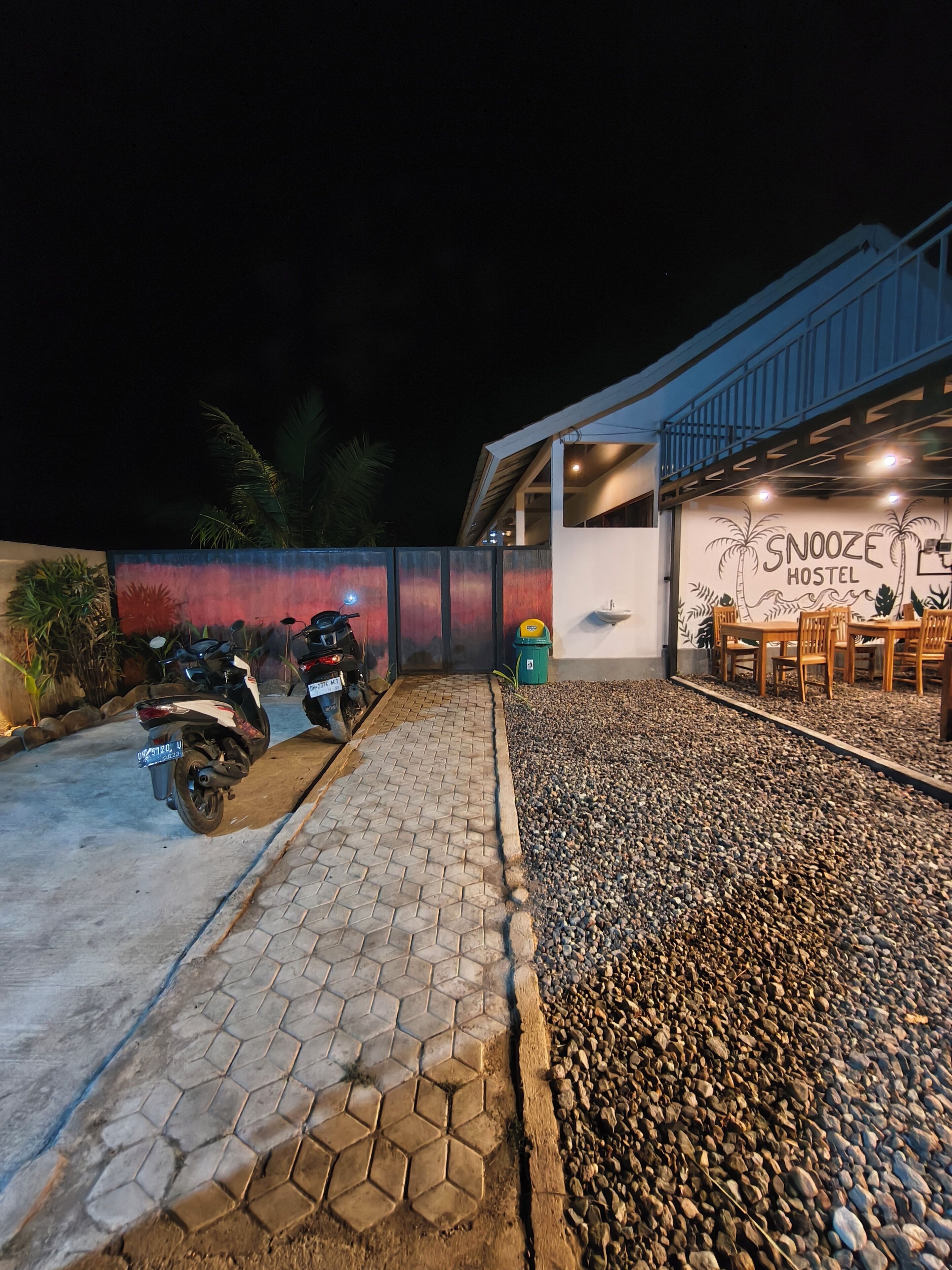 A hostel with a tiled patio, a wall mural, and outdoor seating.