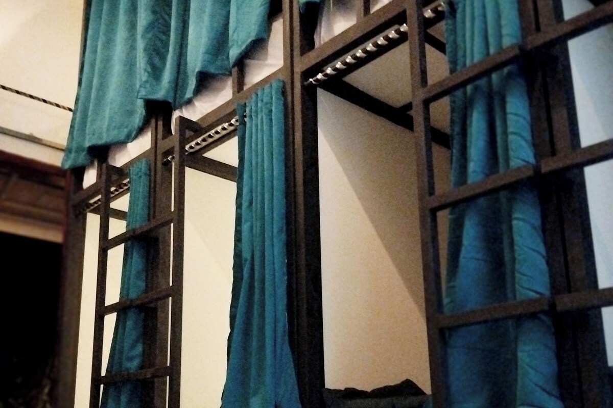 Bunk beds with curtains, a ladder, and a white mattress.