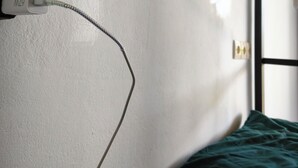 Una cama litera con una lámpara de pared, un enchufe y una ventana con vistas.