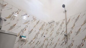 Un baño con inodoro, ducha y paredes con diseño de mármol.