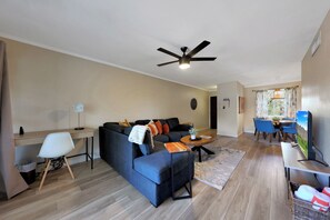 A modern living room with a sofa, a desk, a dining area, and a ceiling fan. - 2BR/2BA Scottsdale Condo with heated pool (Scottsdale)