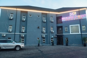 Um edifício com uma placa que diz 'MUSTER POINT HOTEL & SUITES' e várias unidades de ar condicionado.