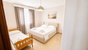 Ett hotellrum med en säng, en stol, ett fönster med gardiner, en tavla som hänger på väggen och en taklampa.