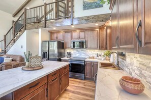A spacious kitchen with wooden cabinets, a marble countertop, and a stainless steel range hood. - The Gold Hill Chalet W/ Private Hot Tub (Keystone)