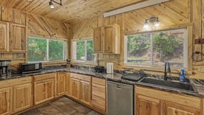 Una cocina con armarios de madera, lavavajillas, pileta y una ventana con persianas.