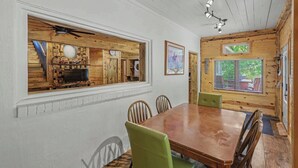 Un interior de madera con una mesa de comedor, sillas, un reloj y una ventana con persianas.