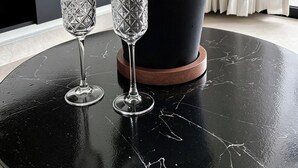 Et bord i sort marmor med en champagneflaske og to krystalglas.