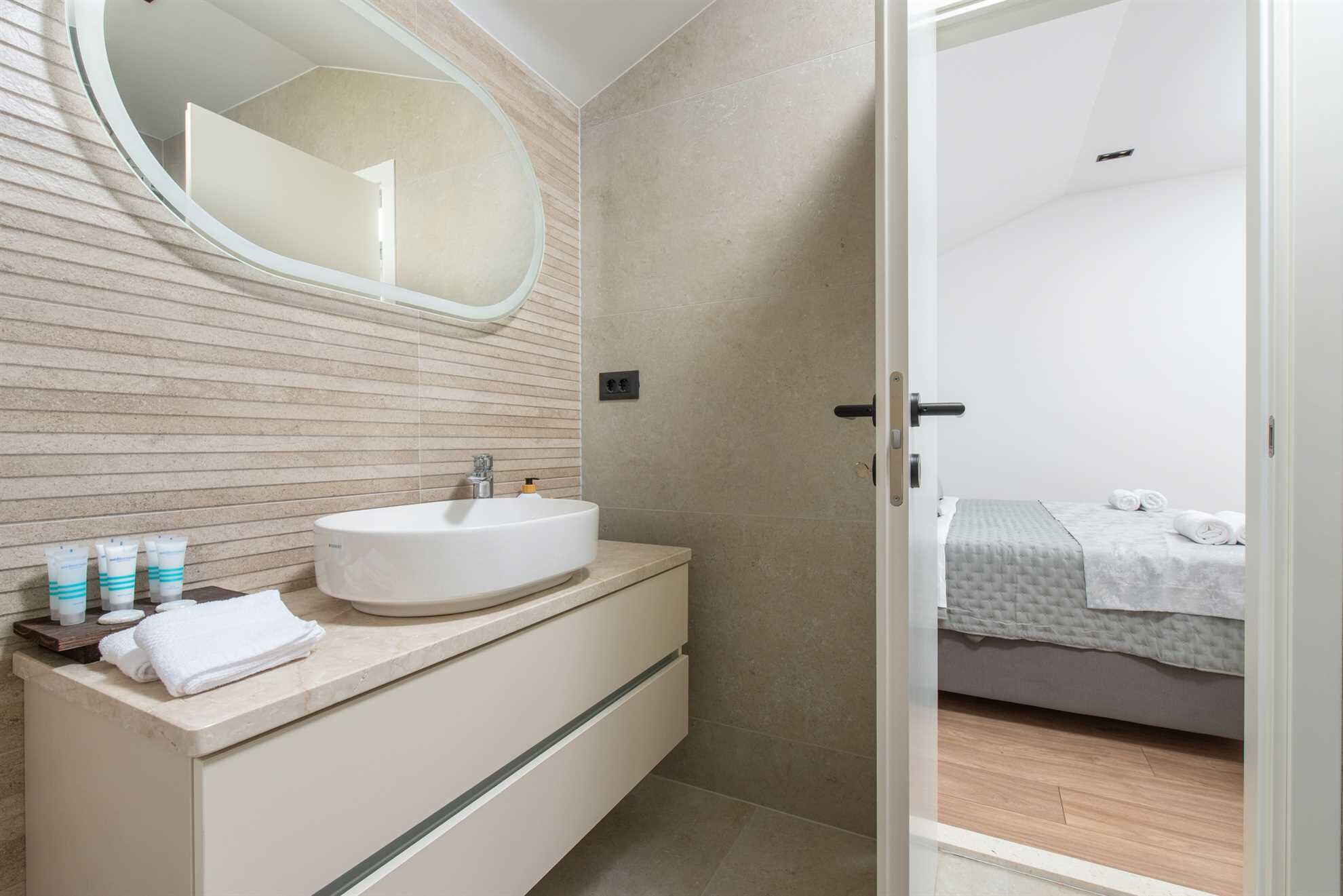 A modern bathroom with a freestanding sink, a large mirror, and toiletries on the counter.