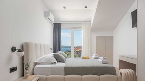 Ein modernes Schlafzimmer mit Bett, Nachttisch, Lampe und Blick ins Freie.