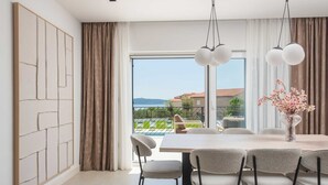 Ein moderner Essbereich mit einem großen Tisch, Stühlen und Blick auf einen Pool und die Landschaft.