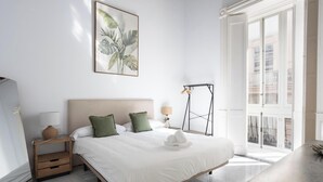 Hotelkamer met een bed, nachtkastje, lamp, wanddecoratie en een raam met uitzicht.