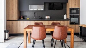 Een moderne keuken met een eettafel en stoelen, een flatscreen-tv en inbouwapparatuur.