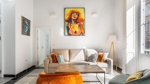 Een moderne woonkamer met een bank, salontafel en een levendig schilderij aan de muur.