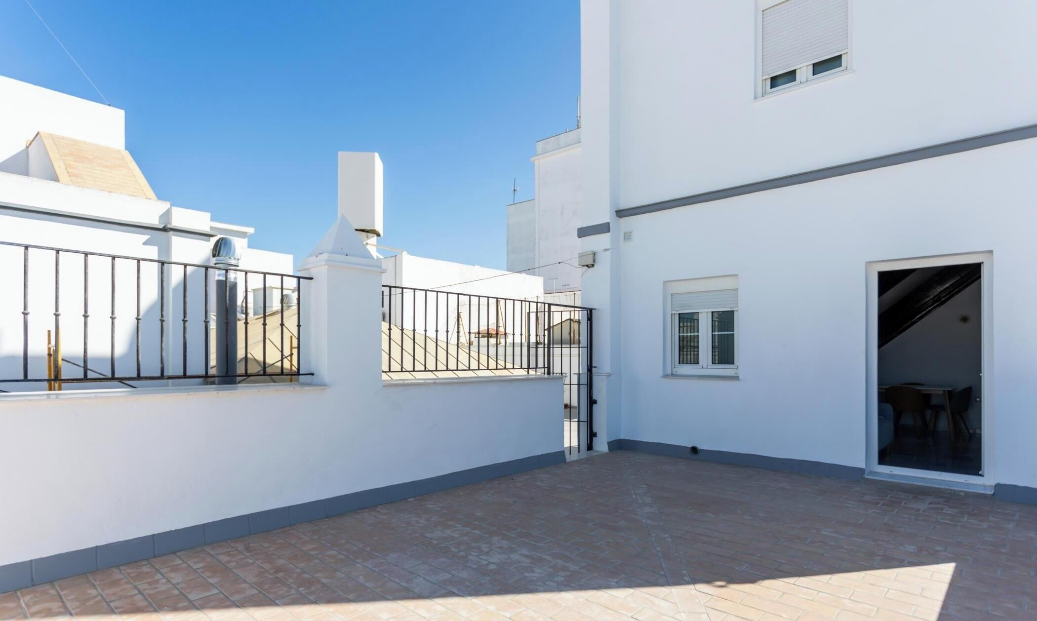 A white building with a gated patio area and a door leading to an interior space.