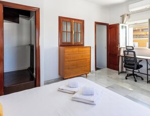 A hotel room with a bed, a wooden dresser, a desk with a chair, and a window with curtains. - Torre Argantonio by LiveWork (Cádiz Cádiz)