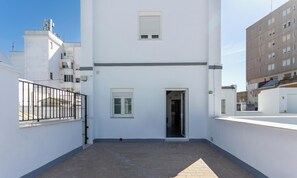 Un bâtiment blanc, doté d’une petite entrée et d’une fenêtre, entouré d’autres bâtiments.