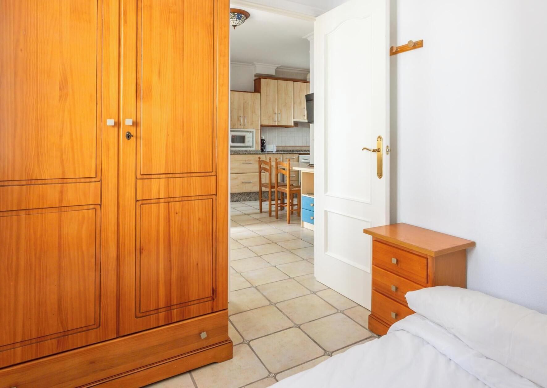 Un dormitorio con un armario de madera, una mesita de noche y una cama.
