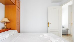 Ein Hotelzimmer mit Bett, Lampe, Tür und Blick auf ein weiteres Zimmer.