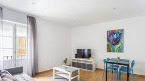 Un salon moderne comprenant un canapé, une table basse, un téléviseur et un coin repas avec des chaises et une table.
