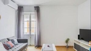 Un salon moderne avec un canapé, une table basse et un téléviseur.