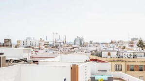 Eine Stadtansicht mit mehreren Gebäuden, darunter ein markanter Turm und eine Brücke im Hintergrund.