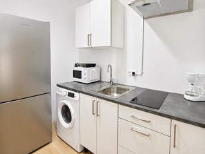 Eine kompakte Küche mit Waschmaschine, Mikrowelle, Spüle und Kaffeemaschine.