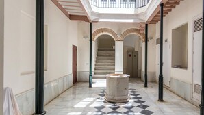 A hallway with a checkered floor, a central column, and a staircase leading to an upper level. - Charming Penthouse in the Heart of Cádiz (Ciudad de Cádiz)