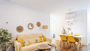 Een woonkamer met een bank, een eettafel met stoelen en een lamp.