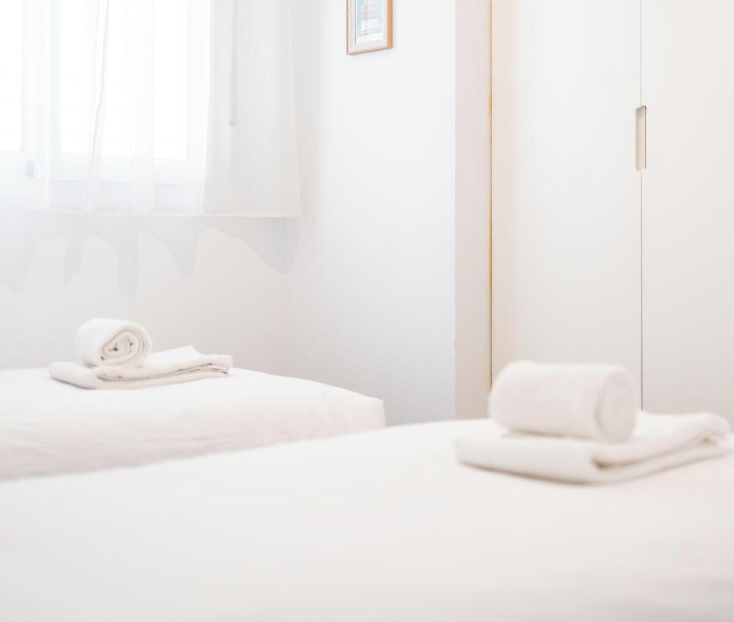 A hotel room with a bed, a bedside table, and a wardrobe.