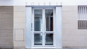 Een gebouw-ingang met een bord waarop 'TORRE 15' staat, boven een dubbele glazen deur met een metalen beveiligingshek.