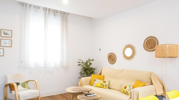 Een woonkamer met een bank, fauteuils, een bijzettafeltje, een lamp en decoratieve wandkunst.