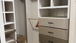 Ein begehbarer Kleiderschrank mit offenen Regalen, einer Kleiderstange und Schubladen.