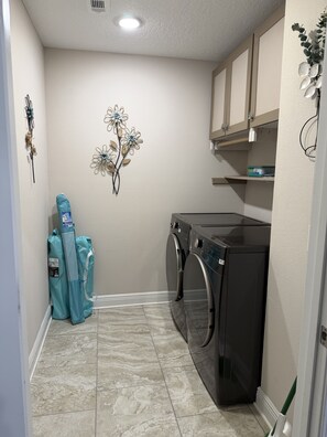 A laundry room with a washing machine, dryer, and a decorative wall piece. - Dual Master Suites~3min Walk to Water ~Sleeps 12 (Gulf Breeze)