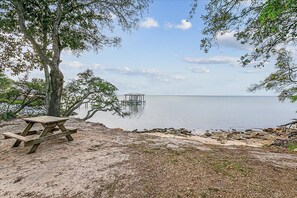A picnic table by a lake with a dock in the background. - Dual Master Suites~3min Walk to Water ~Sleeps 12 (Gulf Breeze)